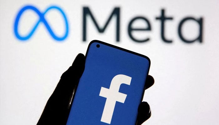 A smartphone with Facebooks logo is seen in front of displayed Facebooks new rebrand logo Meta in this illustration taken October 28, 2021. Photo— REUTERS/Dado Ruvic/Illustration