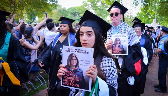 Nooran Alhamdan and her peers walking into the ceremony while holding posters of slain journalist Shireen Abu Akleh. — Twitter/nooranhamdan