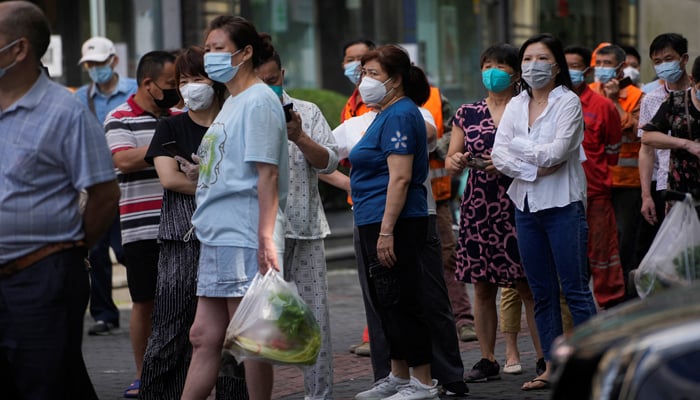 People line up for nucleic acid tests on a street, amid new lockdown measures in parts of the city to curb the coronavirus disease (COVID-19) outbreak in Shanghai, China, June 11, 2022. — REUTERS/Aly Song