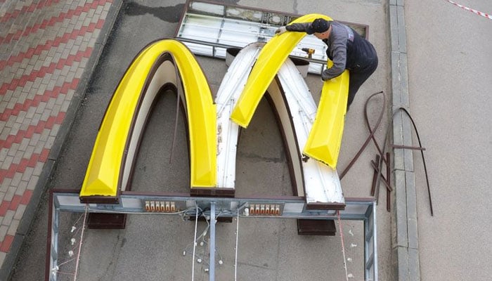 A worker dismantles the McDonalds Golden Arches while removing the logo signage from a drive-through restaurant of McDonalds in the town of Kingisepp in the Leningrad region, Russia June 8, 2022. Photo: Reuters.