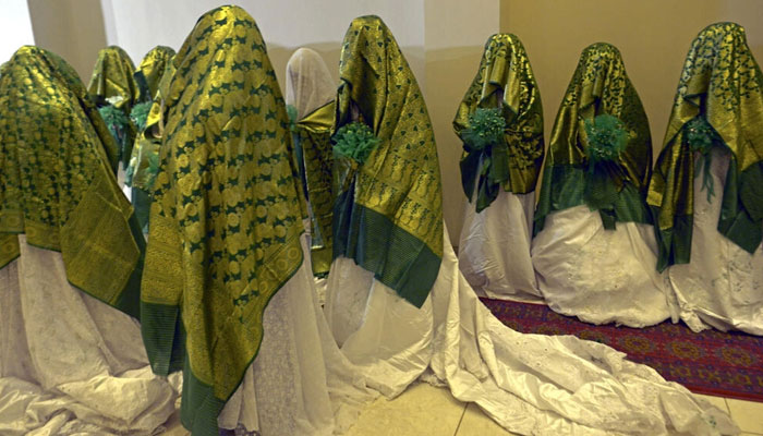 Dozens of Afghan women concealed in thick green shawls were married off in an austere mass wedding in Kabul on June 13, 2022. — AFP
