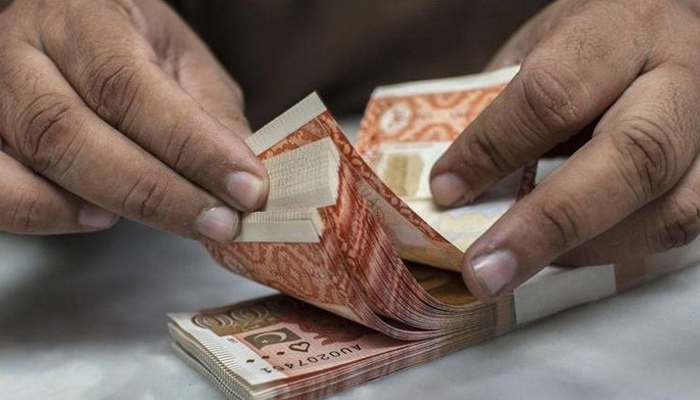 A currency dealer counts Rs5,000 notes. — AFP/File