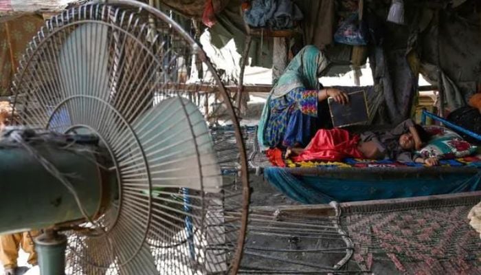 A woman using a paper sheet to fan her child amid a power cut during a heatwave in Jacobabad. — AFP