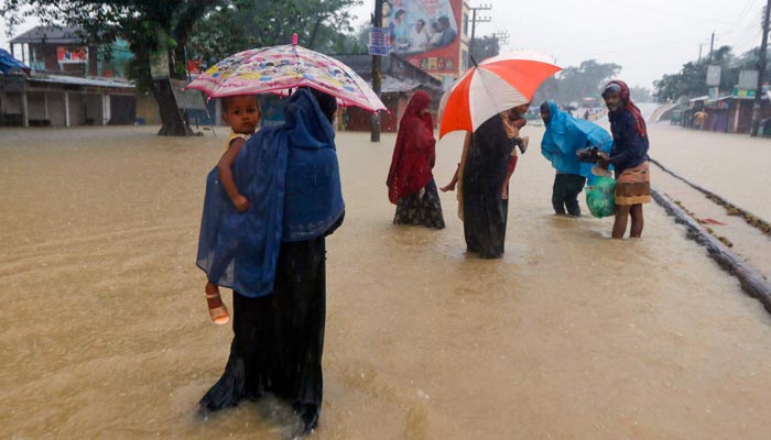 People wade along a road in a flooded area following heavy monsoon rainfalls in Sylhet on June 18, 2022.— AFP/File