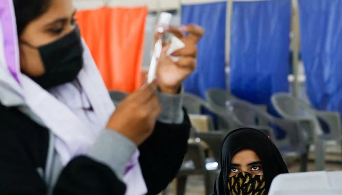 A girl waits as a healthcare worker prepares a dose of coronavirus disease (COVID-19) vaccine to administer at a vaccination centre in Karachi, Pakistan, on January 21, 2022. — Reuters