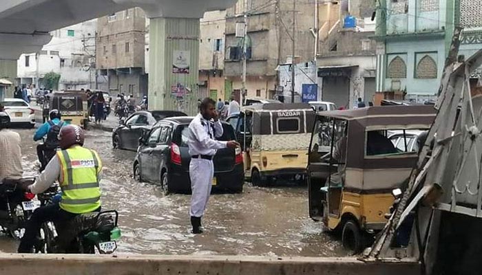 A traffic constable stands in rainwater to help guide the traffic. Geo.tv/File
