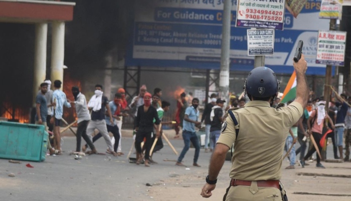 A policeman fires a gun during a protest against Agnipath scheme for recruiting personnel for armed forces, in Patna, in the eastern state of Bihar, India, June 17, 2022. — Reuters/File