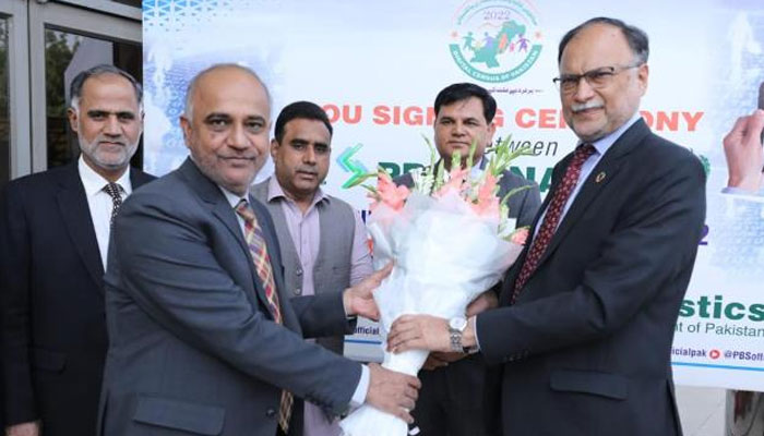 Federal Minister for Planning, Development and Special Initiatives Ahsan Iqbal receives a bouquet at MoU signing ceremony. — APP