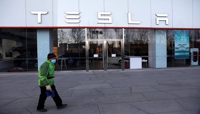 A cleaning worker walks past the electric vehicle maker Teslas showroom in Beijing, China January 5, 2021. — Reuters