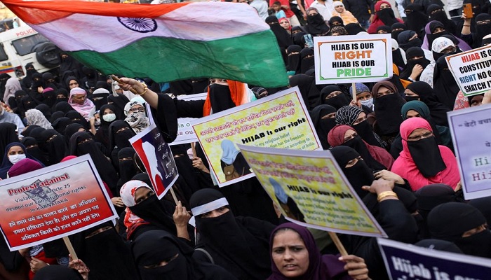 A woman waves the Indian flag as others hold placards during a protest against the recent hijab ban in schools in Karnataka state, on the outskirts of Mumbai, India, on February 13, 2022.—Reuters