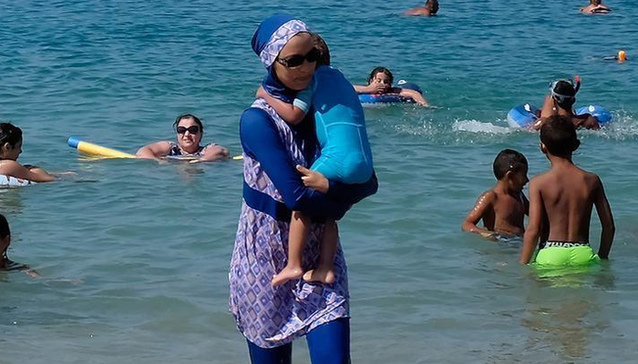A woman wearing a burkini walks in the water on August 27, 2016 on a beach in Marseille, France. — Reuters