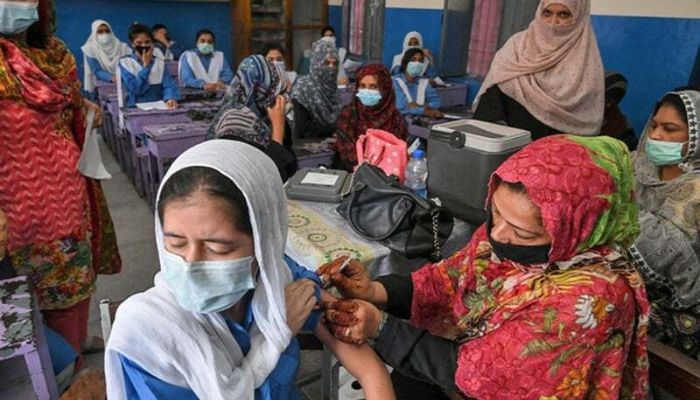 A health worker inoculates a student with a dose of Pfizer vaccine at a school in Lahore. — AFP