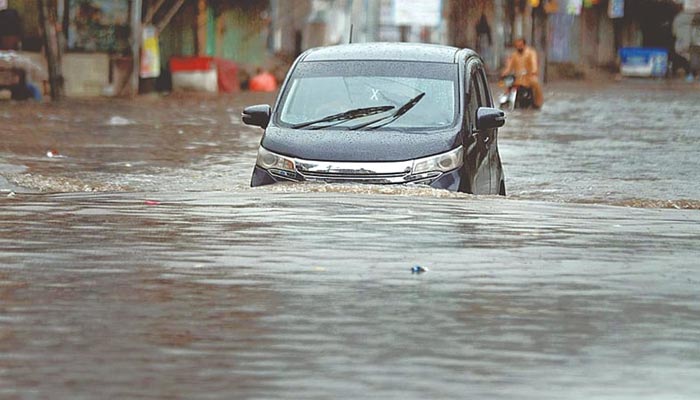 A vehicle passes through standing rainwater. — APP/File