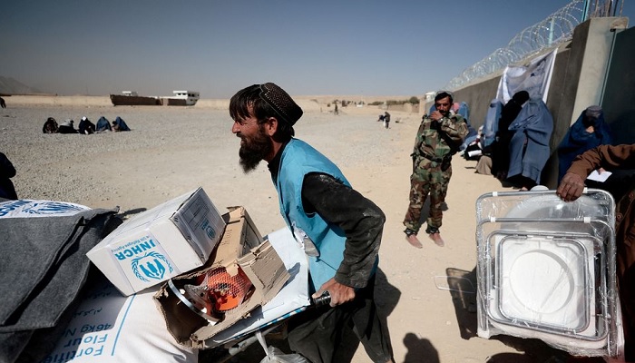 An UNHCR worker pushes a wheelbarrow loaded with aid supplies for a displaced Afghan family outside a distribution center as a Taliban fighter secures the area on the outskirts of Kabul, Afghanistan October 28, 2021.—Reuters