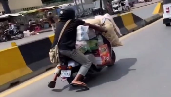 Man rides with a lot of stuff on scooter.—Screengrab via Twitter/@sagarcasm