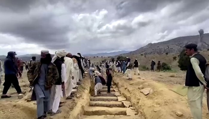 Screengrab of video showing people digging graves to bury the dead after earthquake.  —Reuters