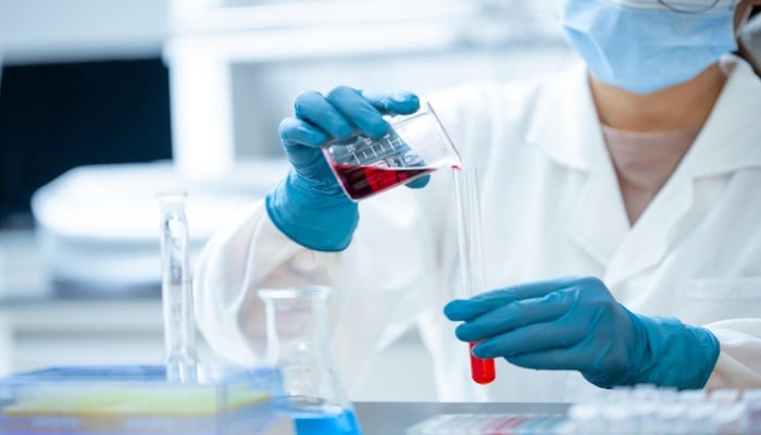 Image showing a person pouring a liquid from a beaker into a test tube. — Pixabay/ BCY