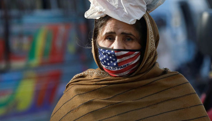 A woman wears a mask to prevent contracting the coronavirus disease (COVID-19) as she carries a bag of supplies on her head in Karachi, Pakistan, January 26, 2022. — Reuters