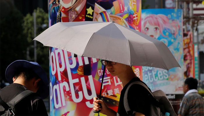 A man uses a parasol on the street of the Akihabara district during a heatwave in Tokyo, Japan August 6, 2018. — Reuters