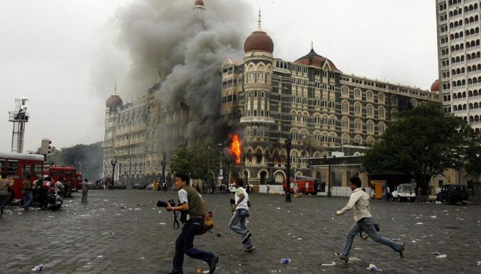 Photographers run past burning Taj Mahal Hotel during a gun battle in Mumbai November 29, 2008. — Reuters/File