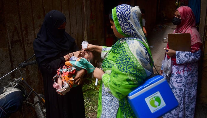 A health worker administers polio vaccine drops to a child during a door-to-door polio vaccination campaign in a slum area in Karachi on June 27, 2022. — AFP