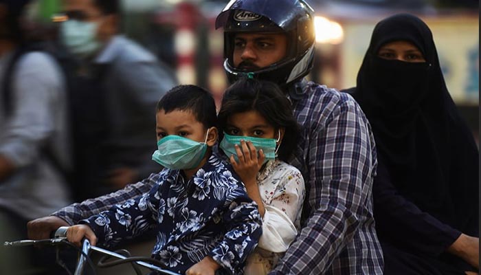 Children riding on a bike with their family wear facemasks as a preventive measure against the coronavirus in Karachi. — AFP/File