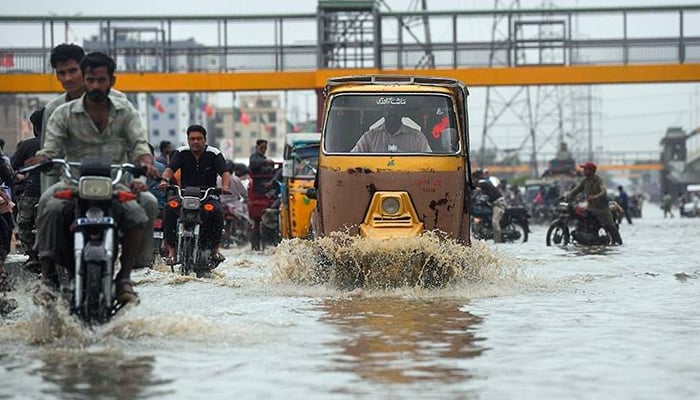 Commuters pass through a road flooded with rain water in Karachi in this AFP file photo.