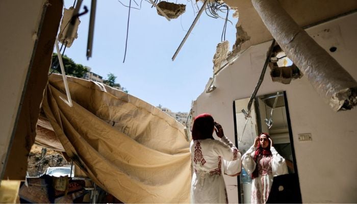 Palestinian bride Rabeha Al-Rajabi looks in the mirror at her house, that was partly demolished by Israeli authority, as part of her pre-wedding ceremony in East Jerusalem June 10, 2022.—Reuters