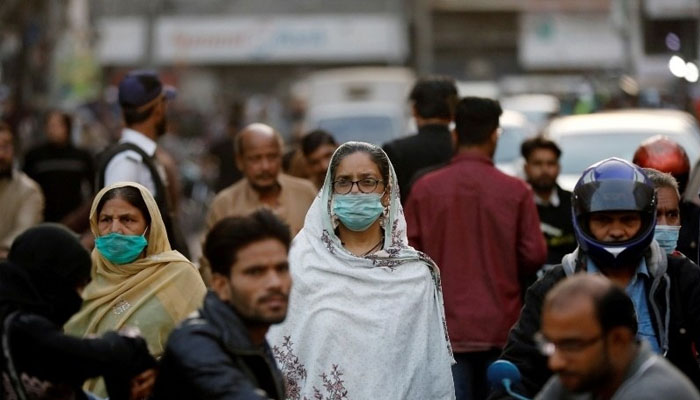 Pedestrians in a market wearing masks amid rising COVID-19 cases in Pakistan. Photo— Reuters