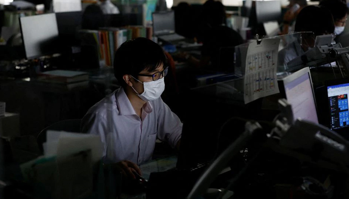 An employee of Tokyo Metropolitan Government office works inside the office with partially switched off lights during daytime to take power-saving measures as Japanese government issues warning over possible power crunch due to heatwave in Tokyo, Japan June 30, 2022. — Reuters