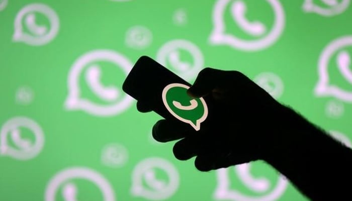 A man poses with a smartphone in front of displayed Whatsapp logo in this illustration September 14, 2017.—Reuters