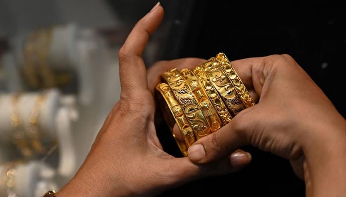 This picture taken on August 11 shows a customer handling gold bracelets at a jewellery shop in Mumbai. — AFP/File