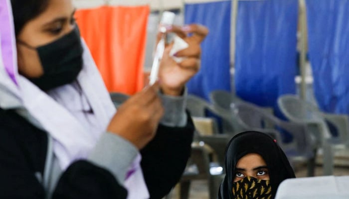 A girl waits as a healthcare worker prepares a dose of coronavirus disease (COVID-19) vaccine to administer at a vaccination centre in Karachi, Pakistan, January 21, 2022. — Reuters