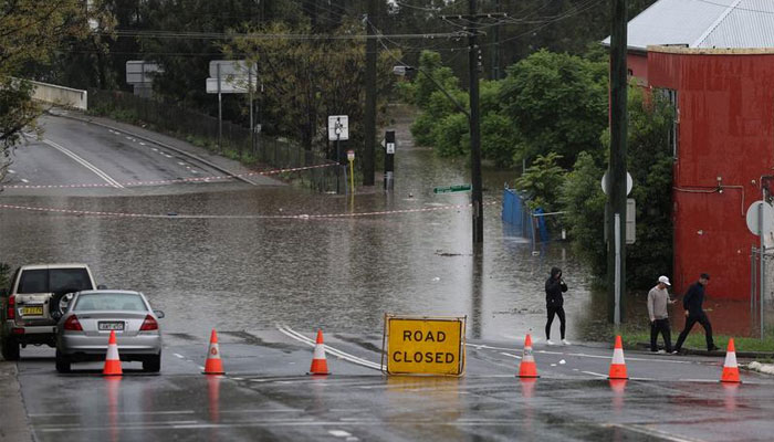 People walk on a street inundated with floodwaters in the suburb of Windsor as the State of New South Wales experiences widespread flooding and severe weather in Sydney, Australia. — Reuters/File