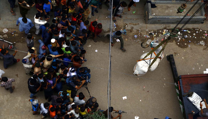 A cow is being lifted down a building using a crane in Nazimabad in Karachi on Sunday, July 03, 2022. — PPI