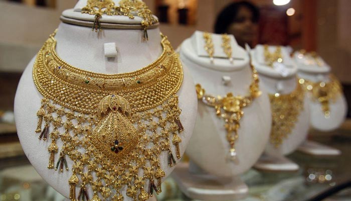 A saleswoman stands behind the showcased gold necklaces at a jewellery showroom in Agartala India on August 18, 2010. — Reuters/File