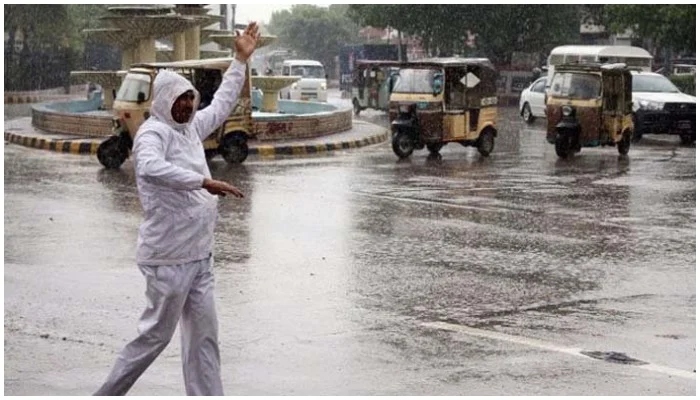 Image showing a traffic warden giving directions to cars amid rain on the streets of Karachi. — Screengrab via Geo News/ File