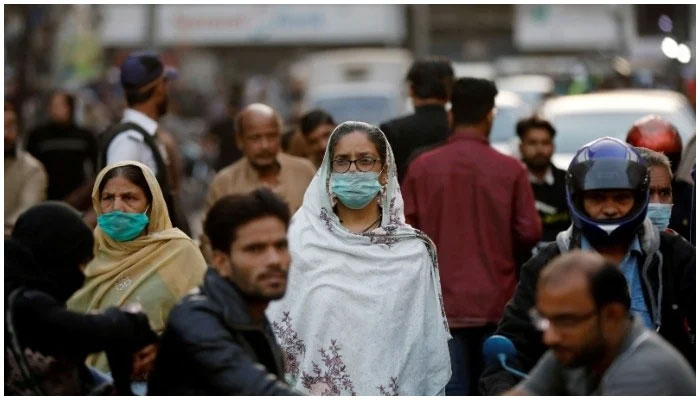 Women wear protective masks as they walk through a crowd along a market in Karachi on Dec 2, 2021. — Reuters