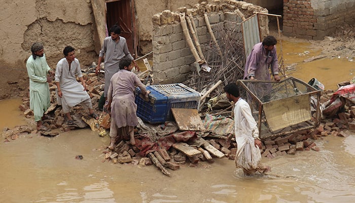 Residents clear debris after the roof of a house collapsed due to a heavy monsoon rainfall on the outskirts of Quetta on July 5, 2022. — AFP