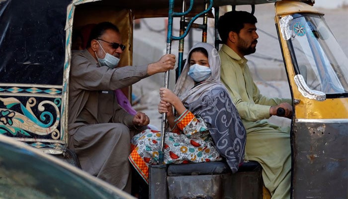 A man rides with his daughter wearing a mask in a rickshaw. — Reuters/File