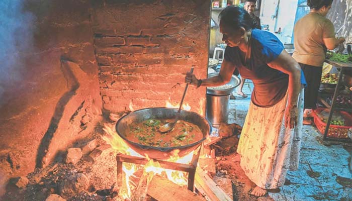A woman uses firewood to cook food at a hotel in Colombo.— AFP