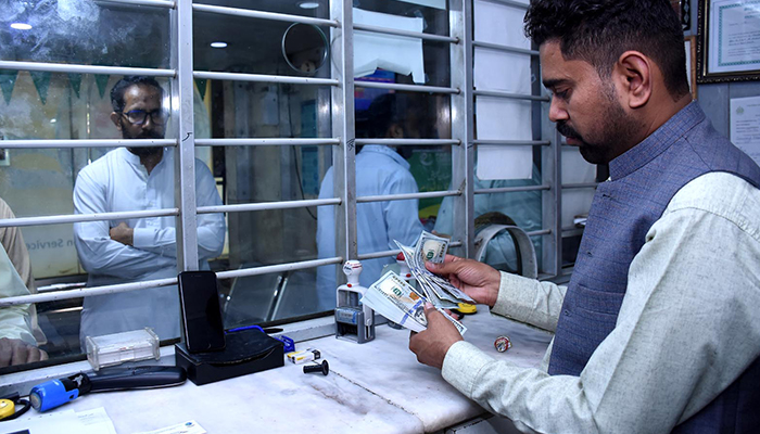 A money changer counts U.S. dollars at a shop in Karachi on April 7, 2022. —Xinhua