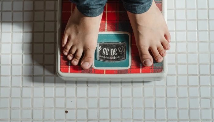 Crop kid weighing on scale.— Pexel