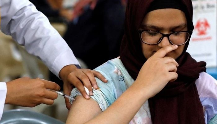 A woman reacts as she receives her dose of coronavirus disease (COVID-19) booster vaccine at a vaccination centre in Karachi, Pakistan June 27, 2022.— Reuters