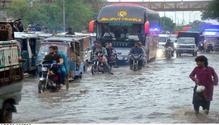 Vehicles passing through rain water accumulated on road after heavy monsoon rain in Karachi. Photo— APP/ Syed Abbas Mehdi