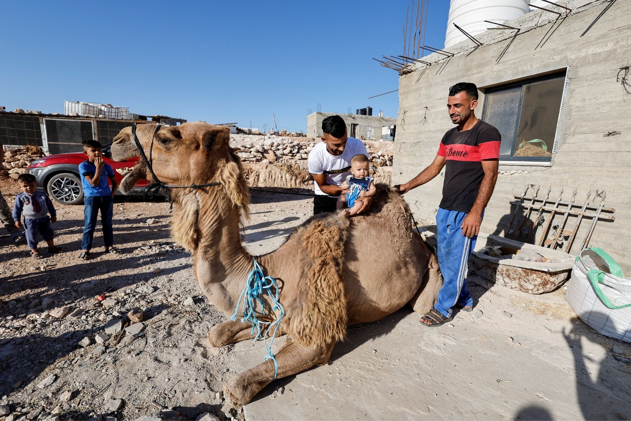 A Palestinian holds a baby ahead of the sacrifice of a camel on the first day of the Muslim holiday of Eid al-Adha, in Yatta, near Hebron in the Israeli-occupied West Bank July 9, 2022.