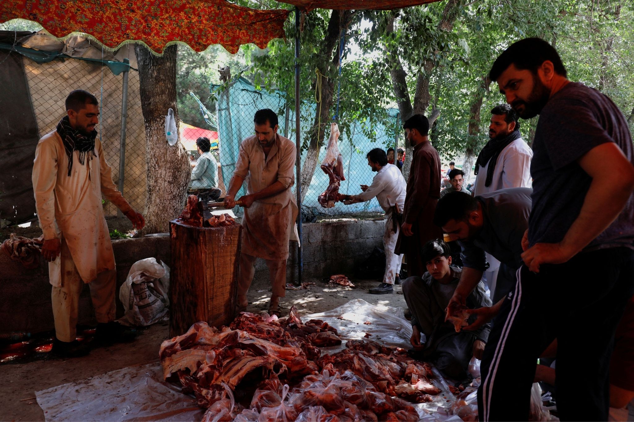افغان مرد 9 جولائی 2022 کو کابل، افغانستان میں عید الاضحی کے پہلے دن گوشت کاٹ رہے ہیں۔