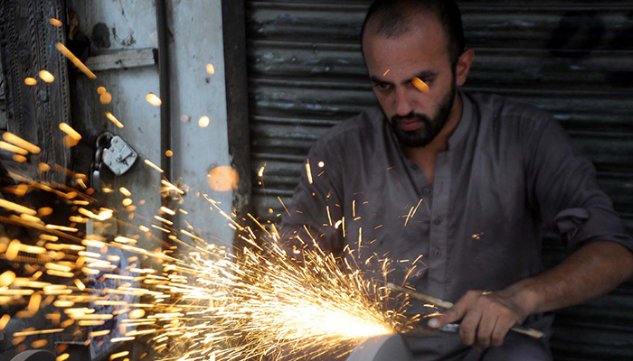 Blacksmiths are busy sharpening and preparing butcher knives for selling ahead of Eid ul Adha at a workplace in Rawalpindi, on July 08, 2022. — PPI