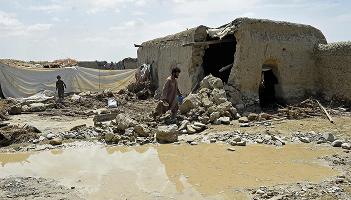 بلوچستان کے ضلع پشین میں 7 جولائی 2022 کو شدید بارشوں کے باعث ڈیم ٹوٹنے کے بعد سیلاب سے متاثرہ رہائشی ملبہ ہٹا رہے ہیں۔ — اے ایف پی/فائل