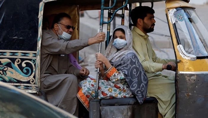 A man rides with his daughter wearing a mask in a rickshaw. Photo: Reuters